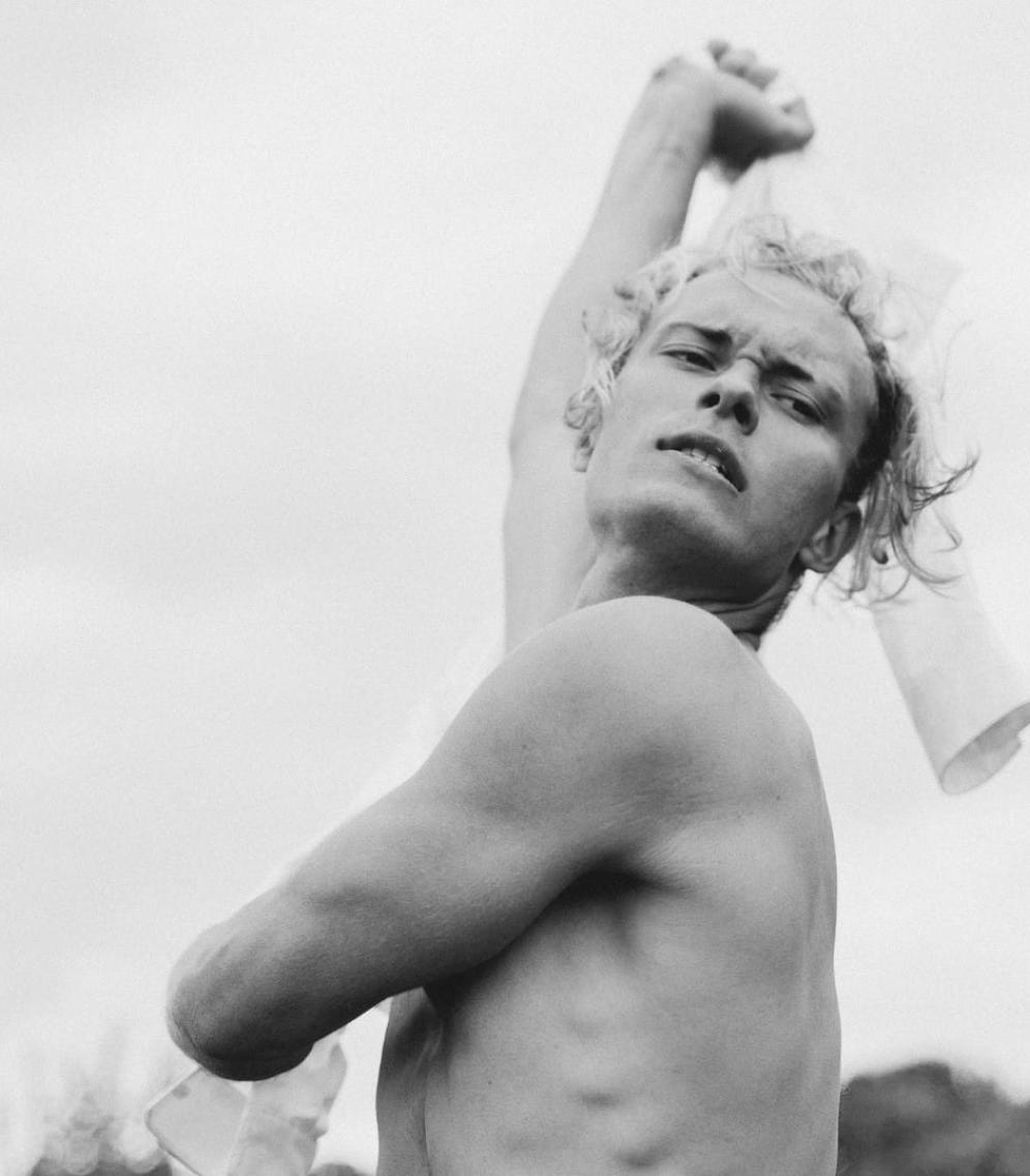 Picture of a toples male dancer outside dancing with a white shirt, facing the camera. 