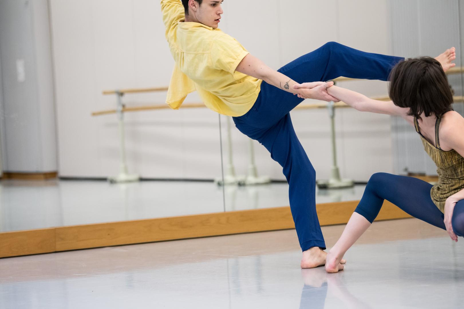 Ein Tänzer und eine Tänzerin im Tanzstudio, mitten in der dynamischen Bewegung fotografiert, sie halten sie an einer Hand fest.