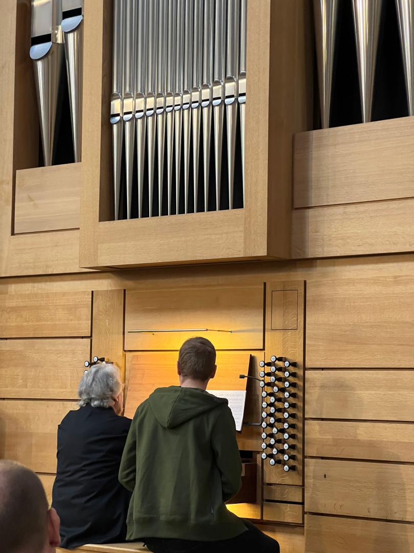 Student sitzt an der Orgel, Daniel Roth sitzt daneben und spielt etwas vor