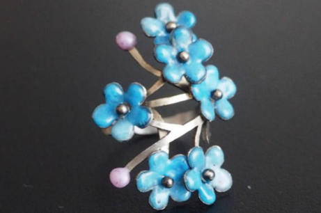 Ein silberner Ring mit sechs kleinen blauen Email-Blumen.