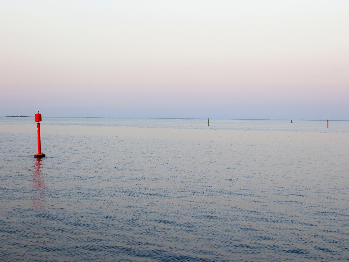 Ein Blick aufs Meer mit einer roten Boje im Vordergrund.