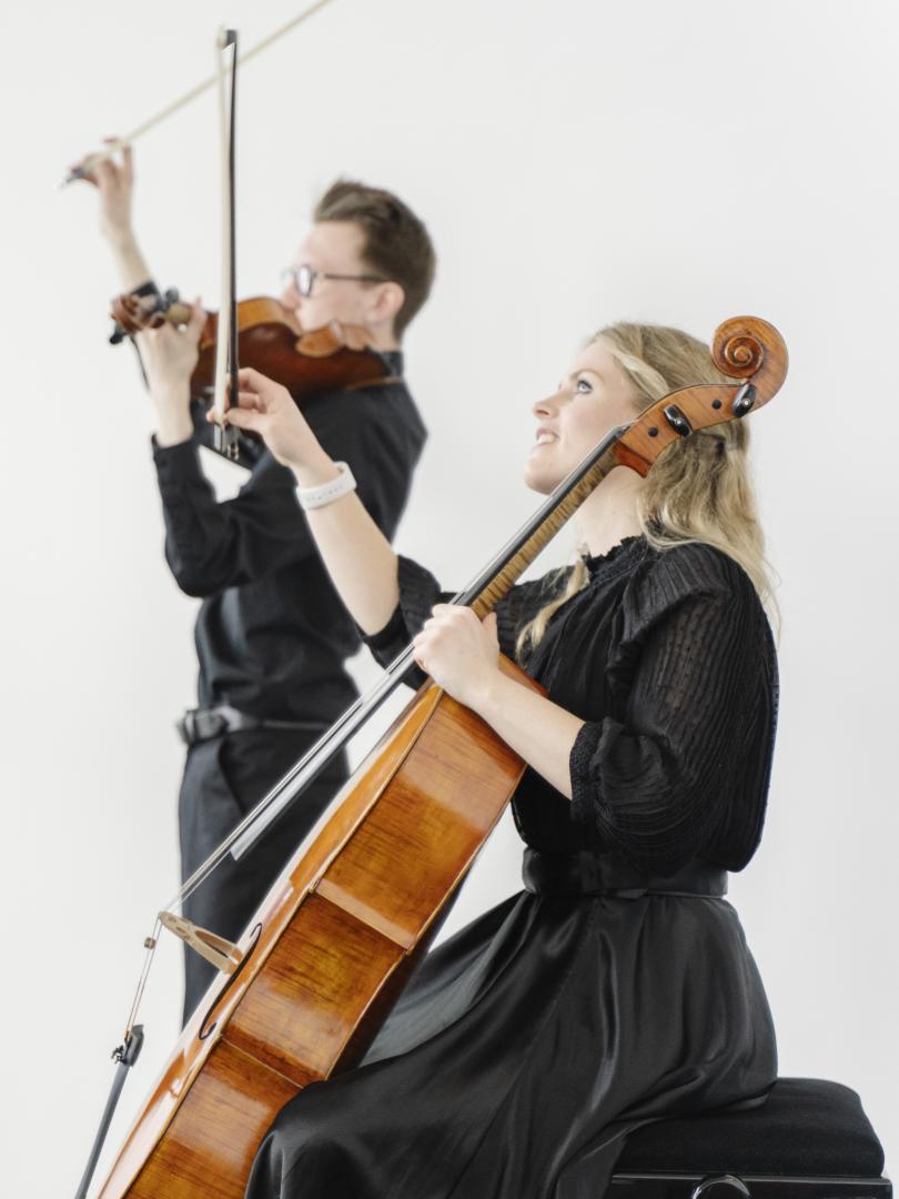 Zwei Musikerinnen eines Streichquartetts während des Konzerts: Im Vordergrund eine Cellistin, im Hintergrund ein Bratschist.