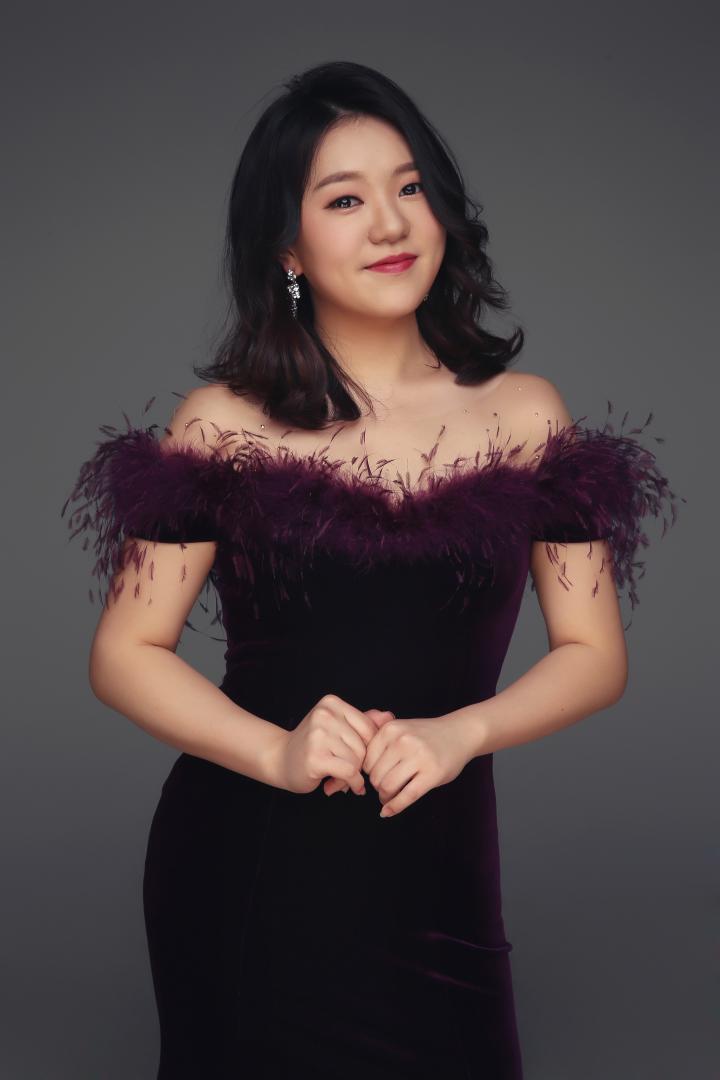 Jessica Seo Jin Lee, in einem schicken, lilafarbenen Kleid, lächelt in die Kamera