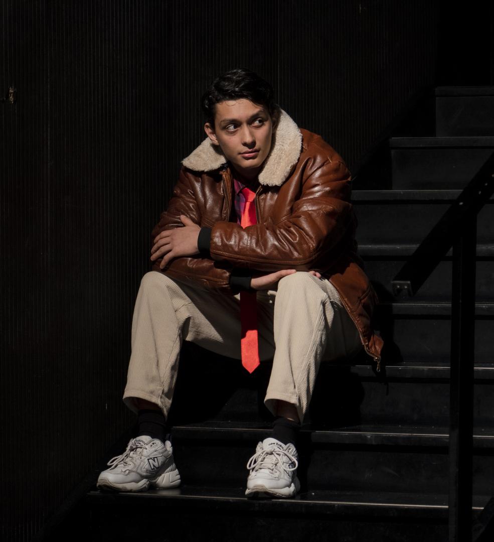 Ein Mann in brauner Lederjacke sitzt auf einer Treppe.