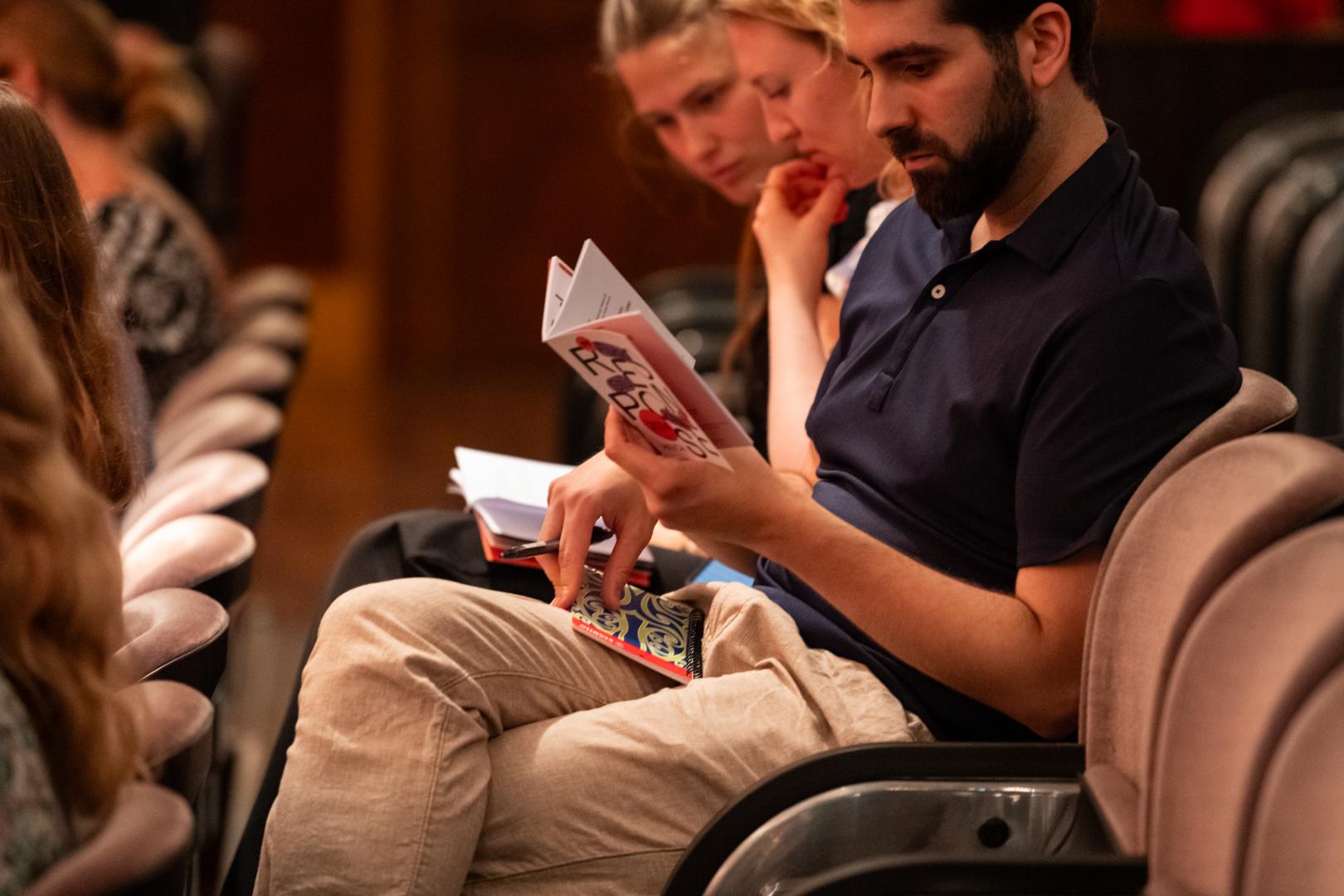 Ein Zuschauer sitzt auf seinem Platz und studiert das Response-Programmheft.