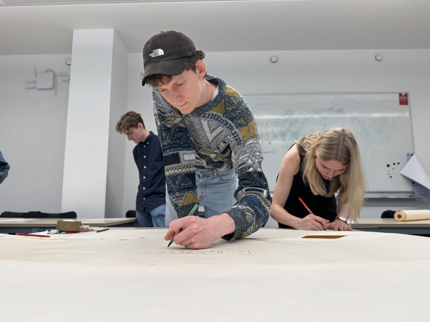 Studierende schreiben auf einem großen Stück Papier