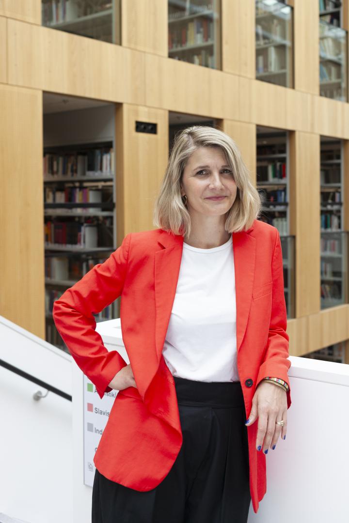 Portraitfoto von Anne Fleckstein vor einer Bibliothek