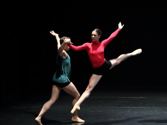 Zwei Tänzerinnen während einer Choreografie, eine Tänzerin mitten im Sprung.