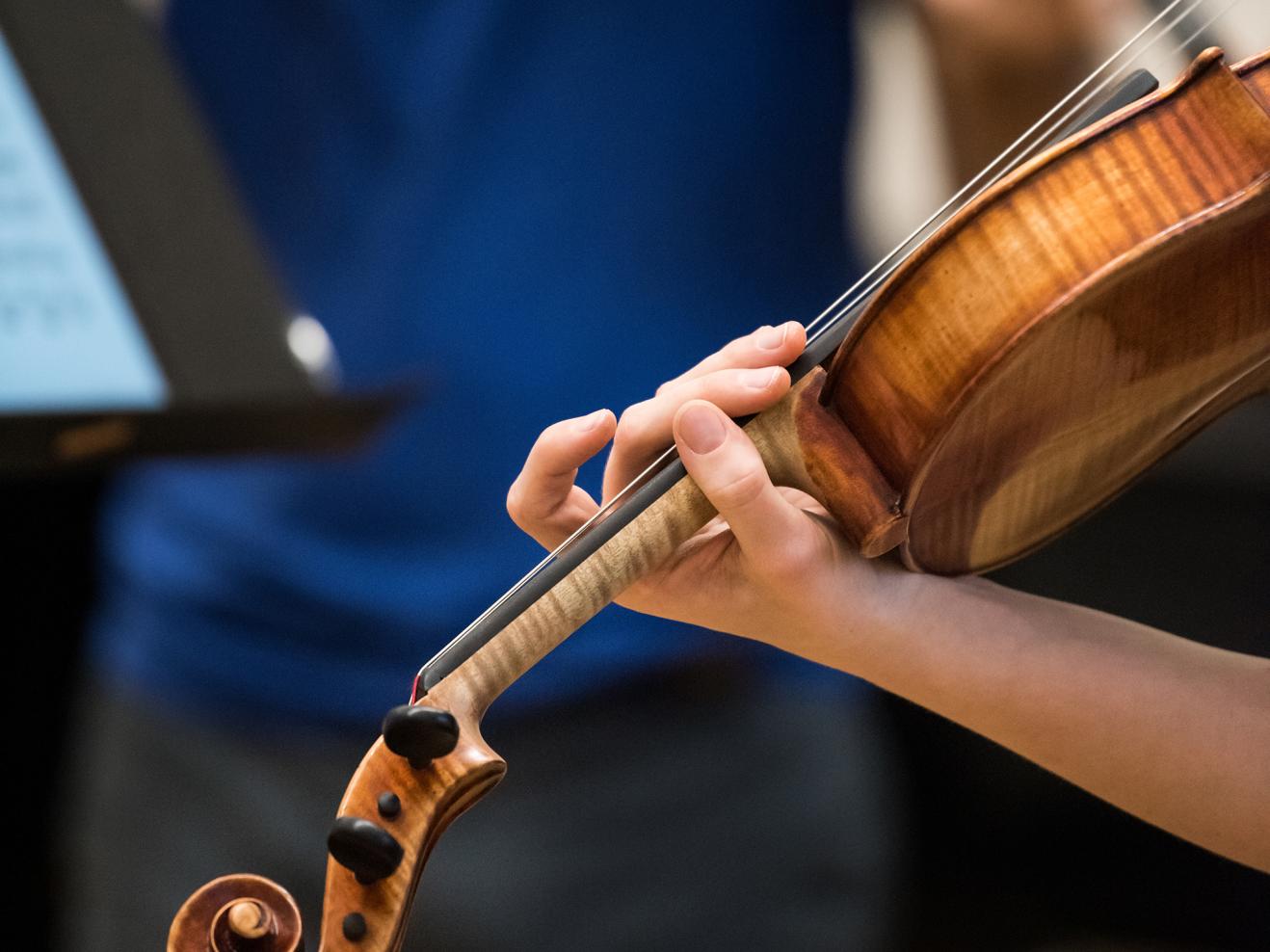 Detailaufnahme einer Hand auf dem Griffbrett einer Viola