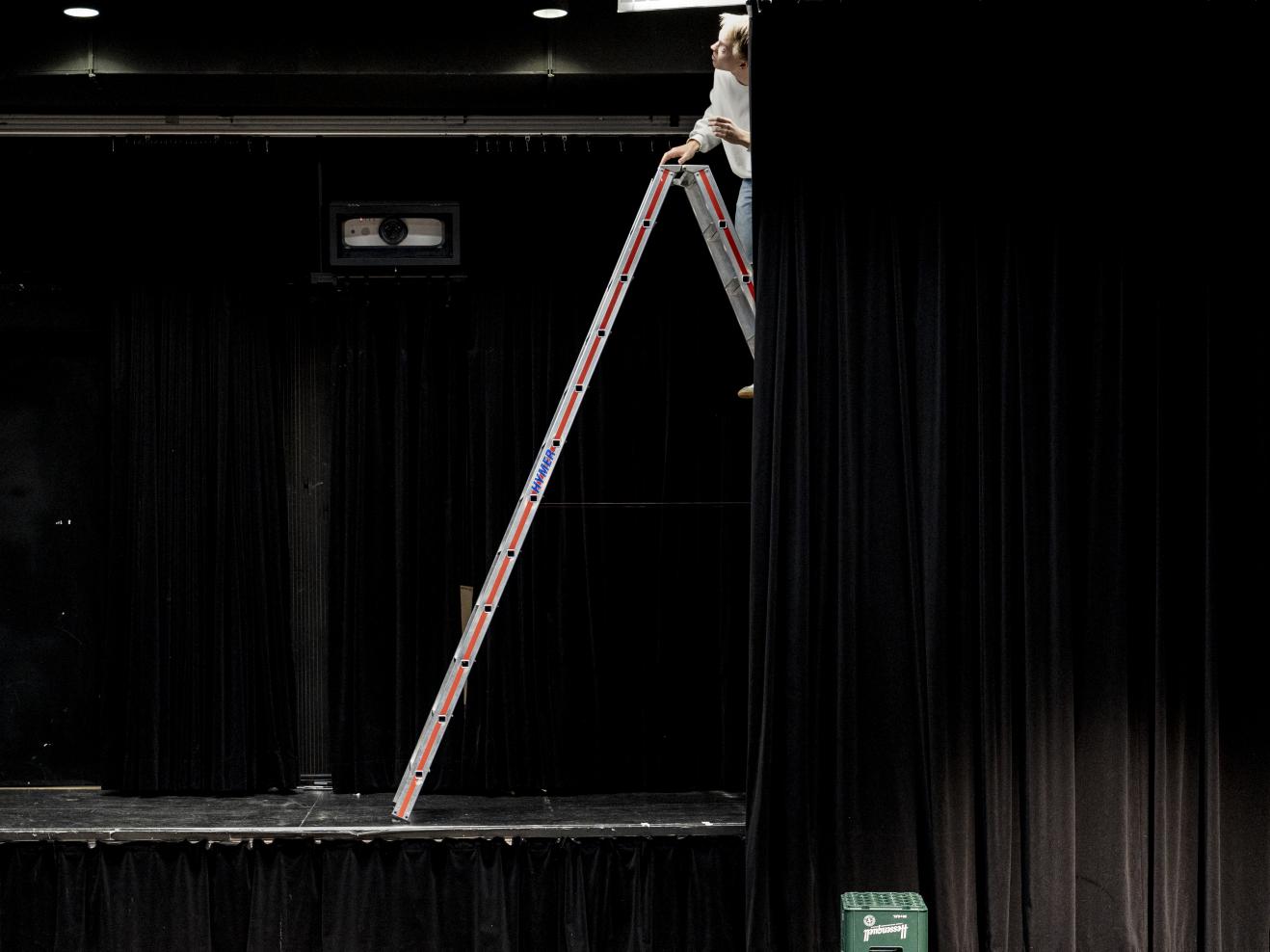 Ein Student steht auf einer Leiter im Schauspielstudio, ganz oben unter der Decke