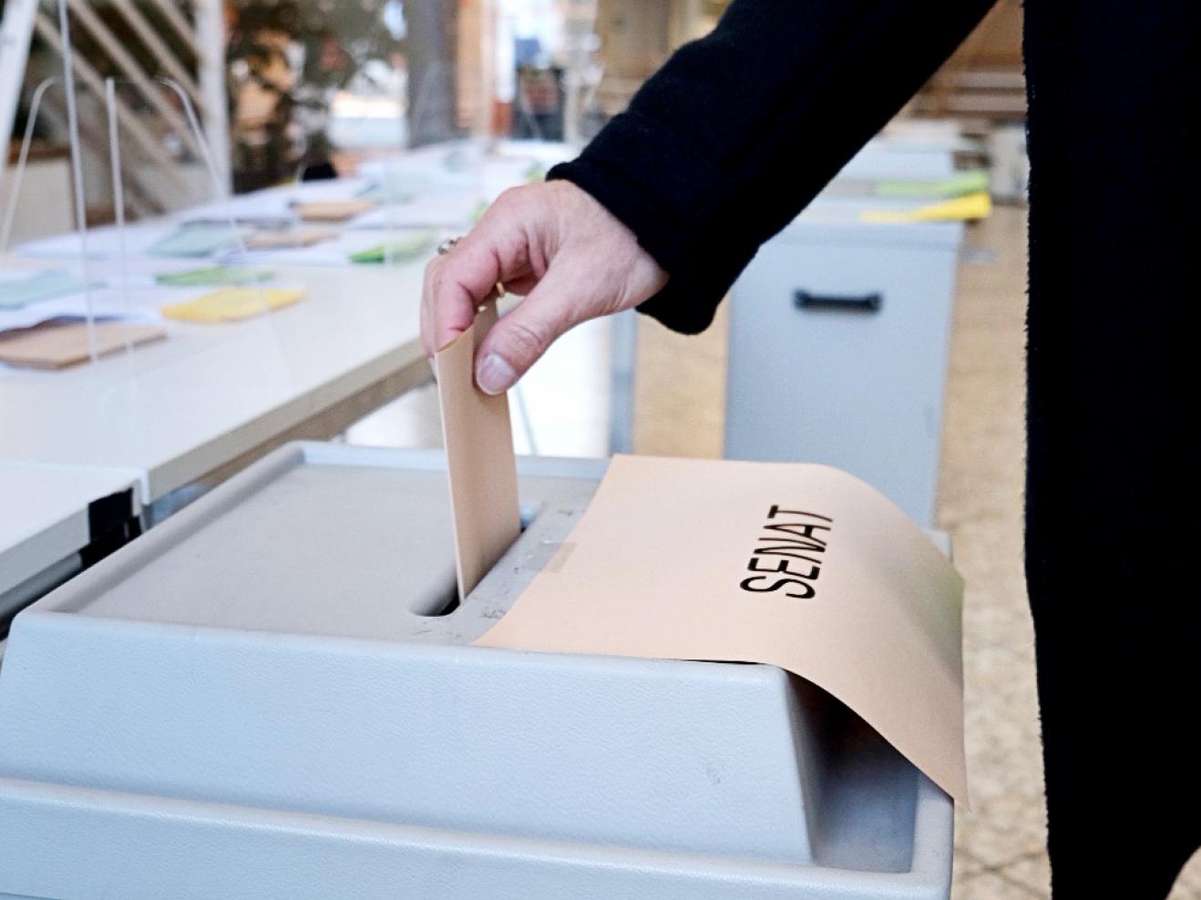 Eine Person wirft einen Wahlumschlag in die Urne bei der Senatswahl der HfMDK.